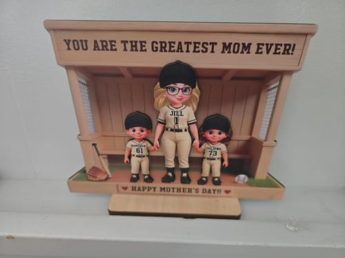 Customer's personalized wooden dugout plaque showing a baseball mom and two kids, displayed on a white shelf.