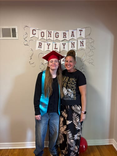 Reviewer wearing the black personalized senior shirt with a custom photo, celebrating with a graduate.