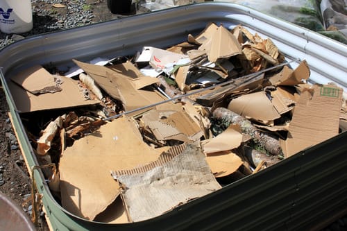 Close-up of a customer's green 17” Tall Modular 9 in 1 bed being filled with cardboard and wood.