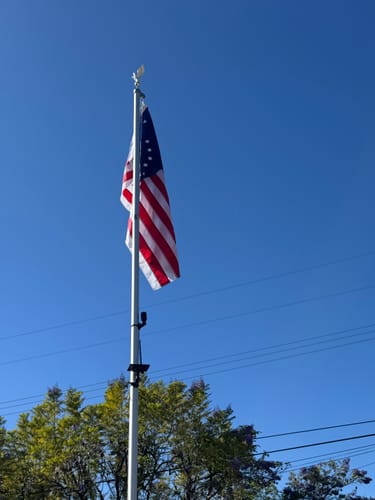 Customer's Bennington Flag hanging on a flagpole against a clear blue sky.