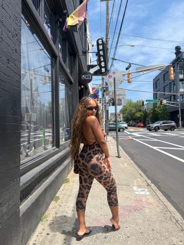 Reviewer on a city sidewalk wearing the leopard print Naked Print Halter Capri Jumpsuit, showing its open-back style.