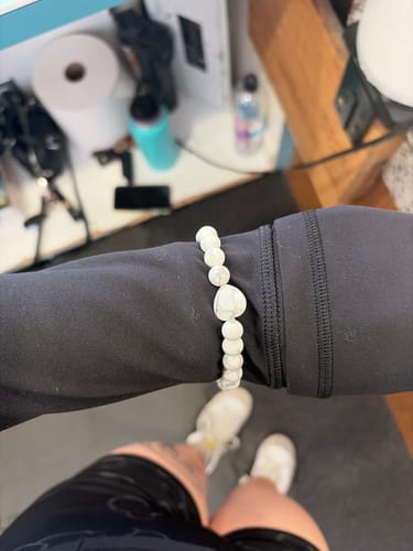 Reviewer wearing the stretchy white howlite crystal bracelet with a heart-shaped bead on their wrist.