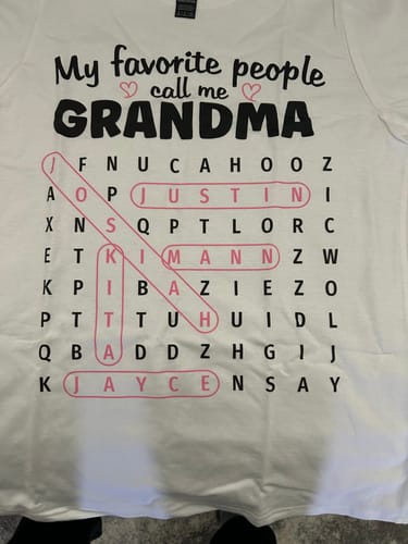 Close-up of a customer's personalized 'Grandma's Favorite People' word search shirt with several names circled in pink.