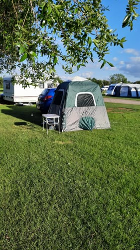 Customer's green and grey Small-Sized 2 Step Cabin Tent pitched on a grassy campsite next to other campers.