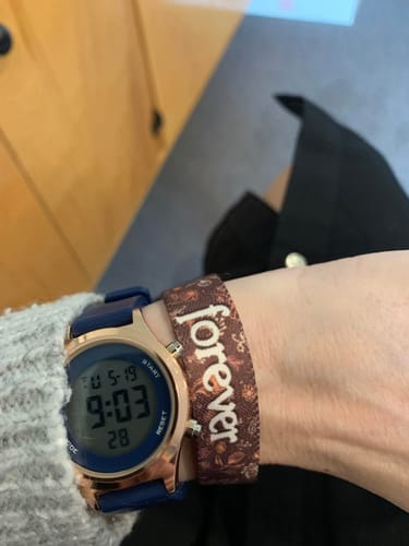 Reviewer's wrist with the Don't Let the Hard Days Win Bracelet fitting snugly alongside a digital watch.