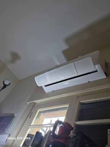 Cliente muestra el Deflector Disperser para Aire Acondicionado instalado en una unidad de aire acondicionado de pared.