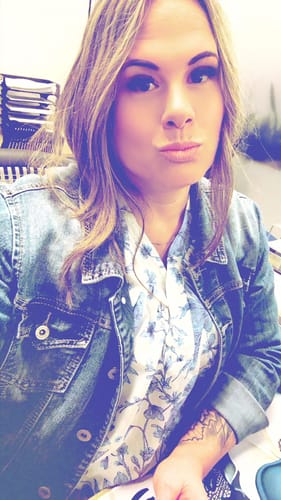 Reviewer wearing the blue and white floral V-neck top layered under a denim jacket.