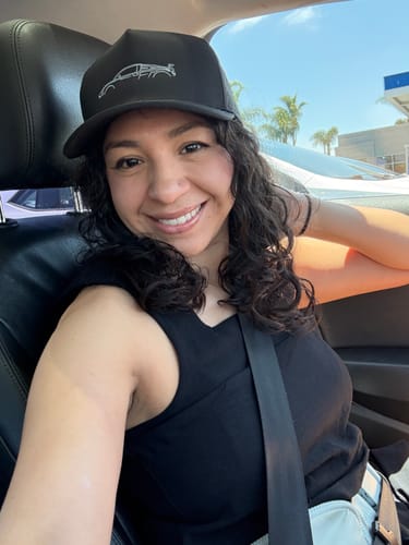 Reviewer smiling in a car while wearing the black 80Eighty® Limited Edition DCG89 Hat.