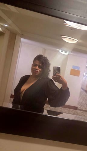 Reviewer taking a mirror selfie in the black Deniz Surplice Mini Dress, showing the deep plunge neck and balloon sleeves.