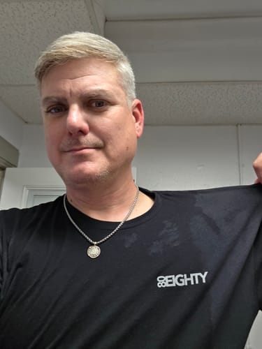 A reviewer wearing the black 80Eighty shirt with a white logo on the chest.