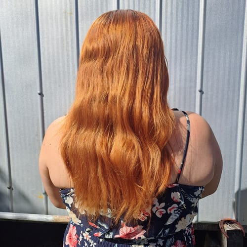 Una clienta muestra su cabello largo y de color cobrizo vibrante, teñido con Henna Jamila.