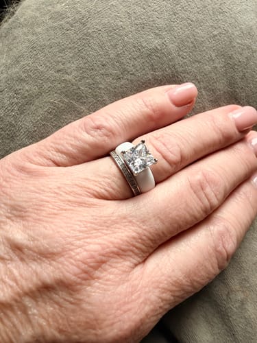 Reviewer's hand showing the white Silicone Ring with a large princess-cut stone, worn stacked with a second band.