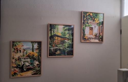 Reviewer's finished Green Old Timer painting, framed and hung on a wall with two other artworks.