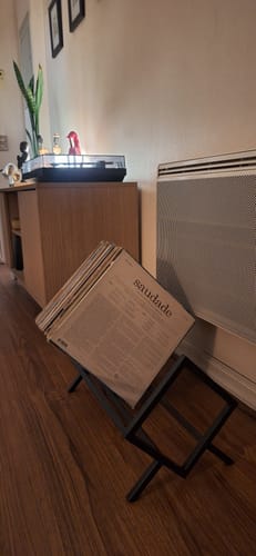 Cliente muestra su porta vinilos negro lleno de discos, colocado en el suelo de madera de un salón.