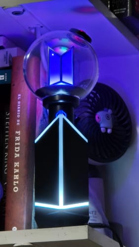 Customer's BTS Official Light Stick Ver.4 and cradle, glowing with a bright blue light.