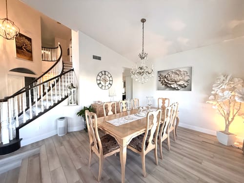 Customer's Elegant White Flower canvas art hung on a white wall in a spacious, elegant dining room with a staircase.