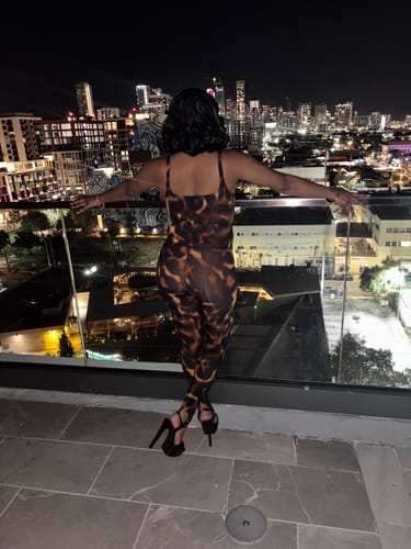 Reviewer from behind wearing the Naked Print Stirrup Leggings as part of a matching set on a balcony at night.
