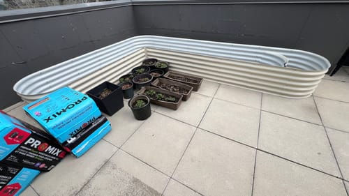 Customer's large, L-shaped modular garden bed set up on a terrace, with soil and plants waiting to be added.