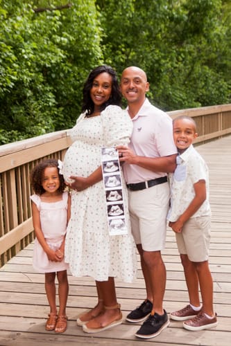 Customer wearing the comfortable Spring Florals Dress while pregnant for family photos on a wooden bridge.