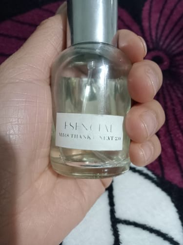 Cliente sosteniendo un frasco transparente del perfume Esencial en la mano.