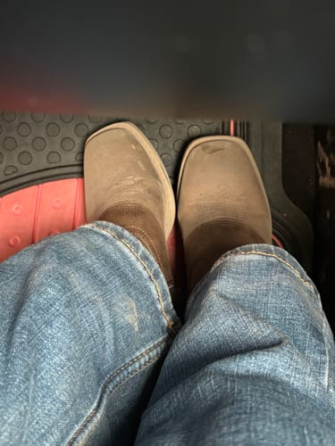 Reviewer's top-down view of their brown square toe western boots, worn with blue jeans.