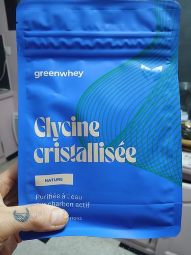 Un client tenant le sachet bleu de Glycine cristallisée dans sa main.