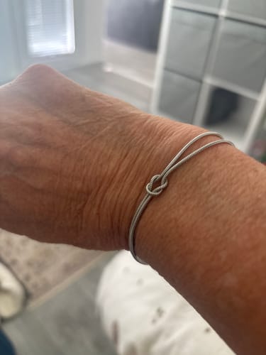 Close-up of a customer's wrist showing a simple silver knot bracelet.