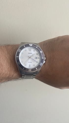 Cliente mostrando su reloj Casio Marlin Duro con esfera blanca y correa de acero en la muñeca.