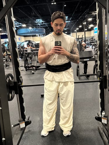 Reviewer in a gym showing the baggy, wide-leg fit of the off-white Encore Track Pants.