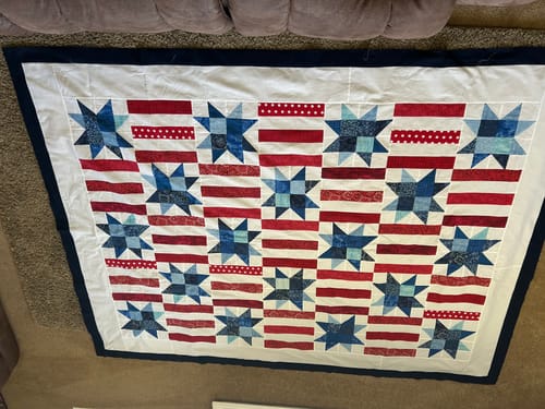 Customer's assembled Red, White, and Cute quilt top with a star and stripe pattern, laid out on a floor.