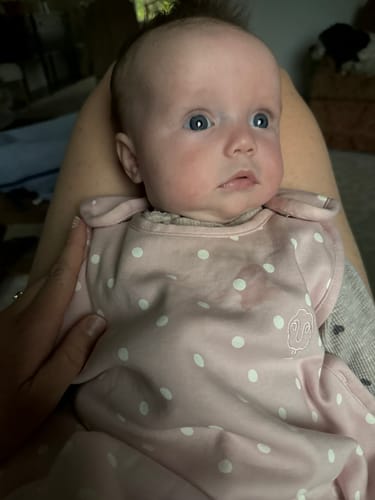 Customer's baby wearing the rose-colored Ultimate Baby Sleep Bag with white polka dots.