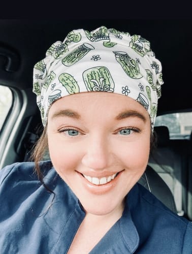 Close-up of a customer smiling and wearing the DuoStyle Scrub Hat with a fun pickle pattern.