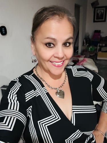 Reviewer smiling confidently, showing her bright smile while wearing Pop On Veneers in a home setting.