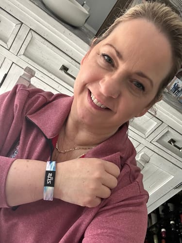Reviewer smiling while wearing a colorful Mindfulness Pack bracelet on their wrist.
