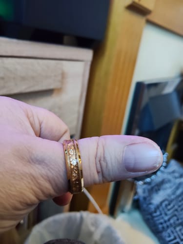 Close-up of a reviewer's thumb wearing the gold Aureum ring with its textured inlay.