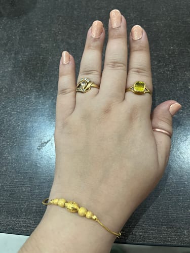 Reviewer's hand wearing the Golden Havana Bracelet, showing its textured gold beads and delicate chain.