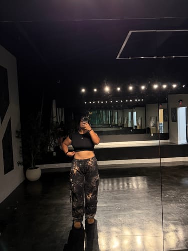 Reviewer taking a mirror selfie in a studio, wearing baggy Heritage Camo Cargo Sweats.