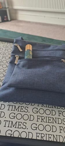 Customer shows the Bag Size for Travel spray inside the front zippered pocket of a blue bag.