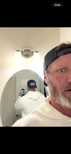 Reviewer wearing the Jesus King Foam Trucker Hat backwards in a mirror selfie, showing the back of the hat in the reflection.