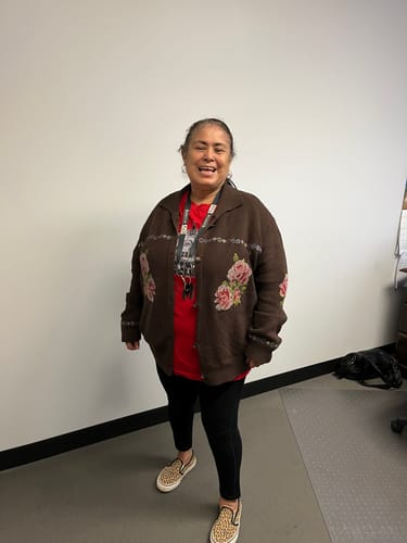 Customer smiles while wearing the brown Nana's Rose Garden Sweater with visible floral embroidery.