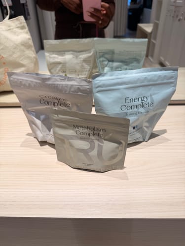 Customer's pouch of Energy Complete among other TRU supplements on a wooden counter.