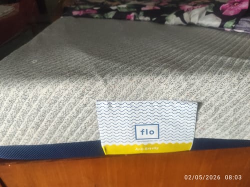 A customer's Flo Anti-Gravity™ Mattress on a bed, showing the textured grey cover and blue side.