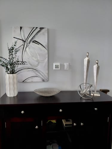 Customer's Winds of Change canvas art hung on a gray wall above a dark console table with various decor.