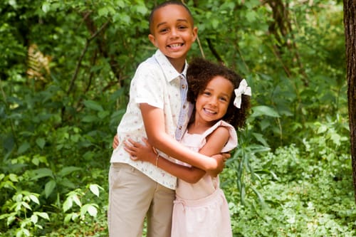 Customer's daughter wearing the Spring Florals Hair Bow while hugging her brother outdoors.