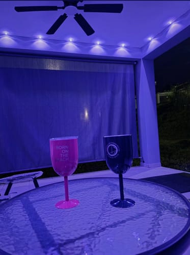 Reviewer's pink and black OL Wine Goblets on an outdoor table under purple lights.