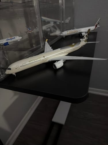 Reviewer's detailed HERPA ETIHAD A350-1000 model airplane displayed on a black shelf among a larger collection.