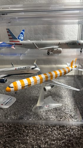 Customer's HERPA CONDOR A321 model with yellow and white stripes displayed on a stand in a case.