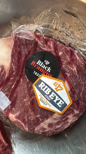 Cliente mostrando un corte de carne Rib Eye en su empaque al vacío.