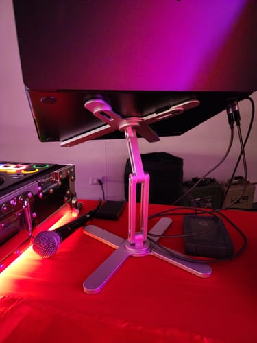 Customer's Model-X 2.0 Stand holding up a laptop as part of a DJ setup on a red table.