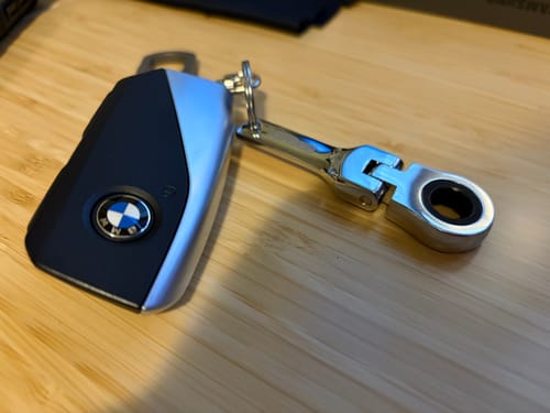 Customer's shiny 10mm Wrench Keychain attached to a car key fob on a wooden surface.